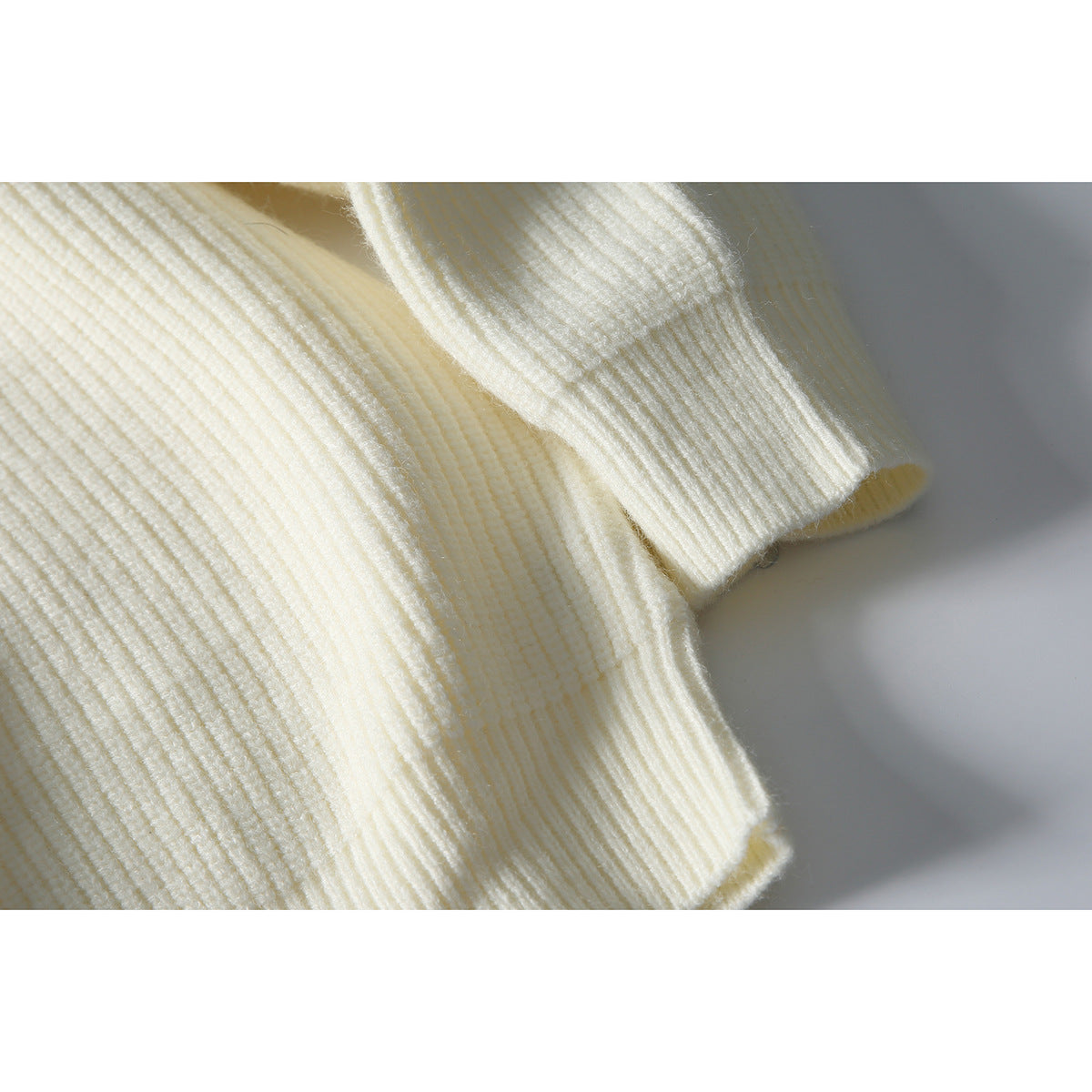 Close-up of the ivory ribbed sweater's sleeve cuff and knit texture.