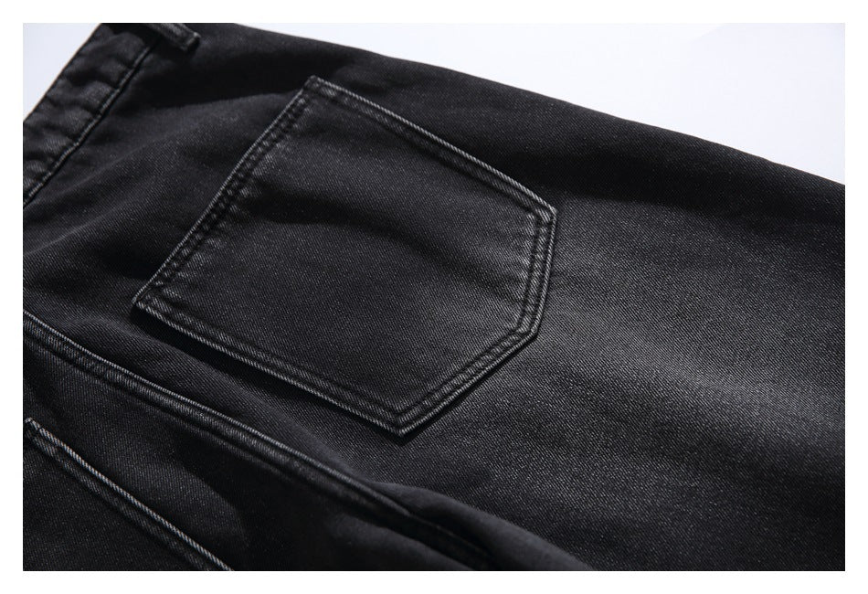 Close-up of a stitched back pocket on black jeans with visible denim texture.