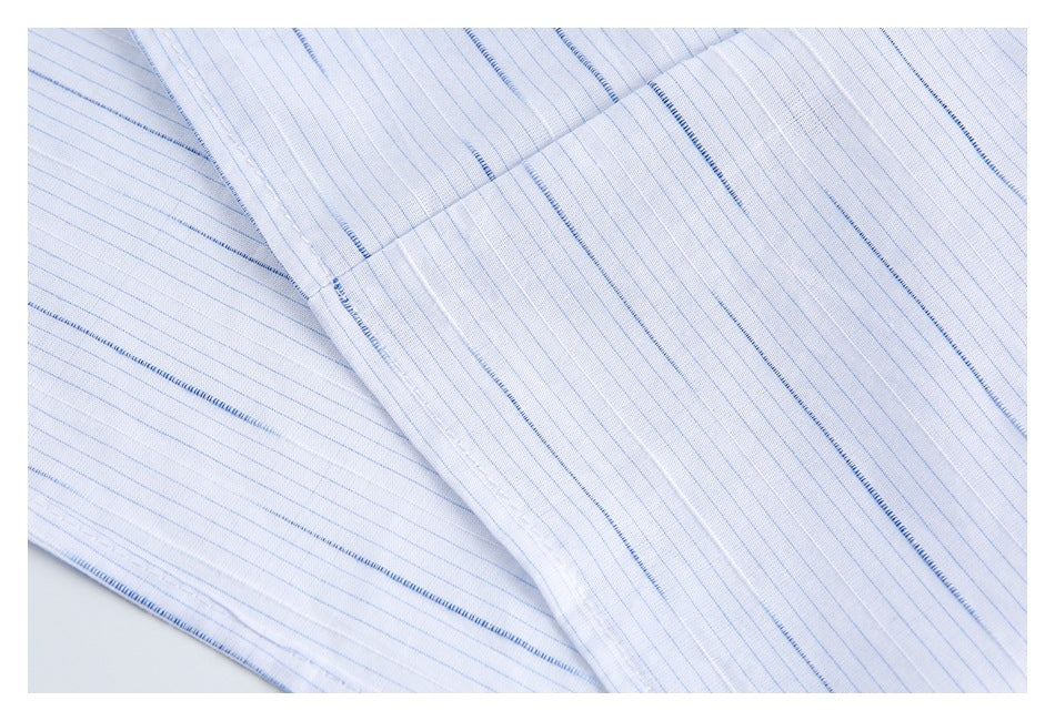 Close-up of overlapping white shirt fabric panels with fine blue stripes and stitched seams.