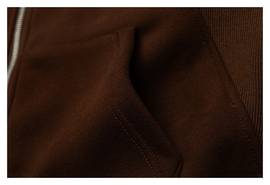 Close-up of the brown sweatshirt's stitched pocket opening and ribbed trim.