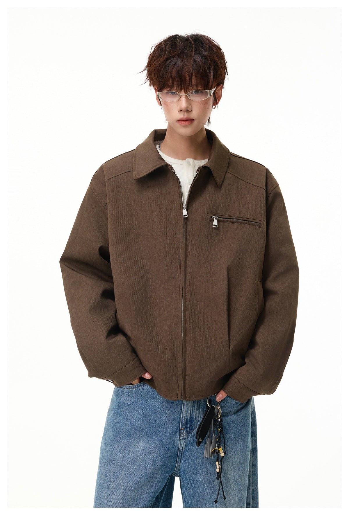 Front view of a model wearing a brown zip-front jacket with a pointed collar and chest zip pocket.