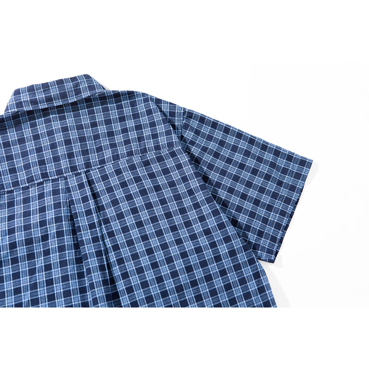 Close-up of the back of a navy plaid short-sleeve shirt, showing the yoke and center pleat.