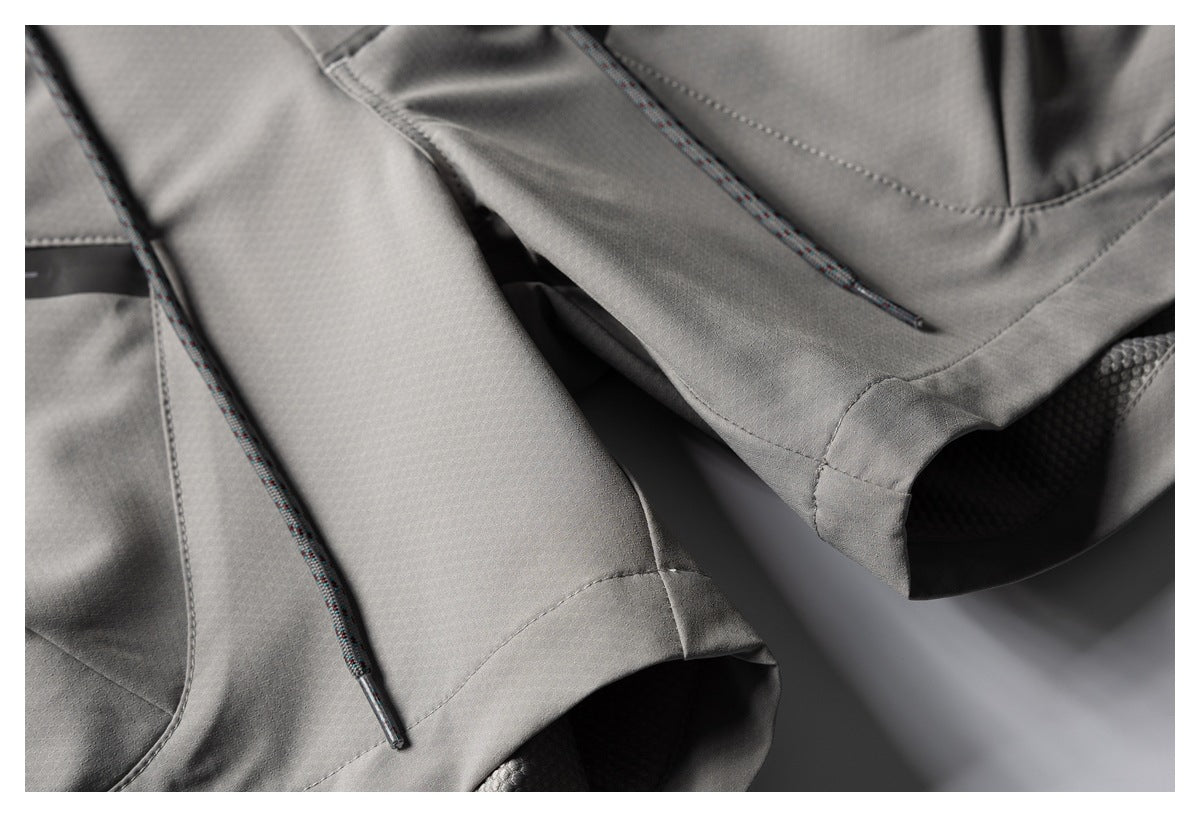 Close-up of gray trouser hems, seams, and multicolored drawcords.