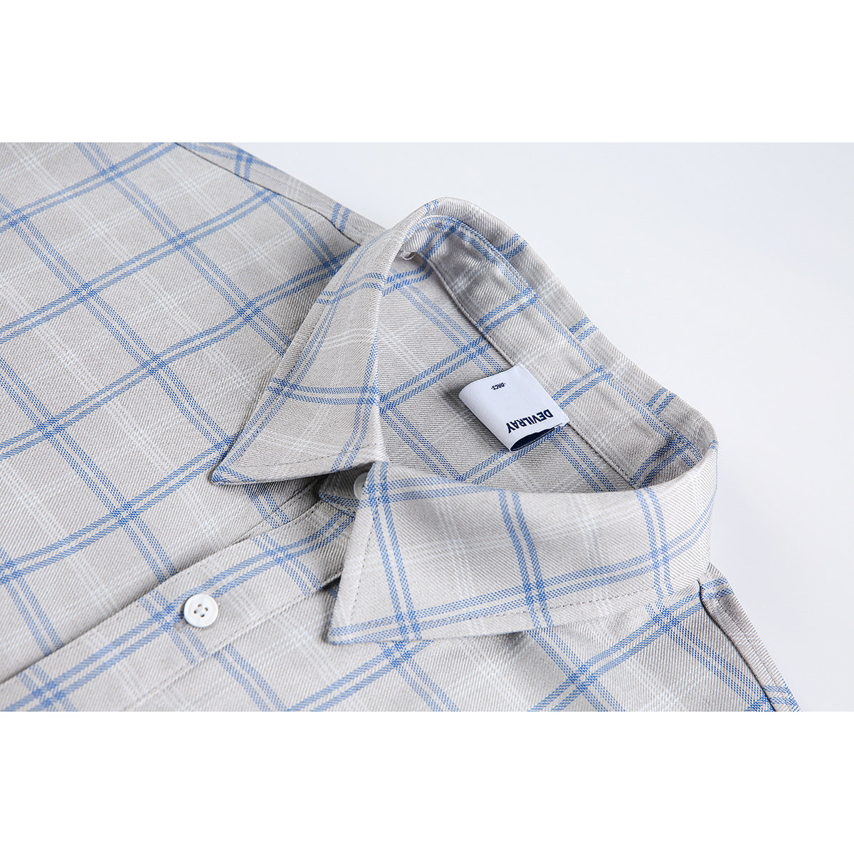 Close-up of a gray plaid shirt collar with blue lines, a white button, and a small neck label.