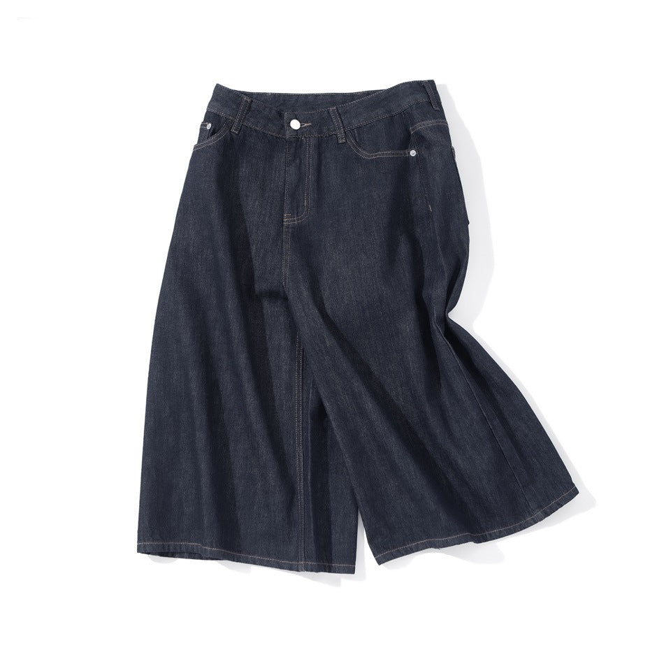 Dark indigo wide-leg knee-length denim shorts laid flat at an angle, showing front fly and pockets