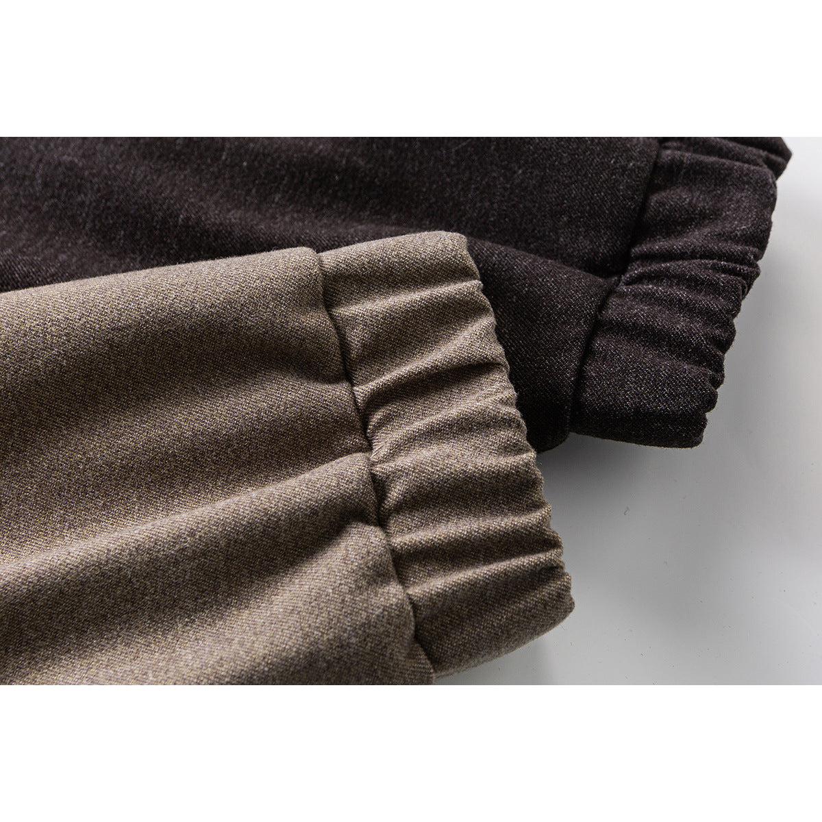 Close-up of gathered jacket cuffs in taupe and charcoal, showing the textured fabric.