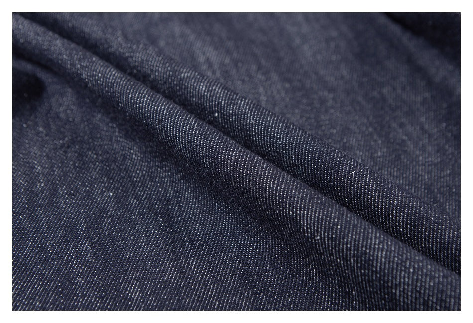 Close-up of dark indigo denim showing its woven texture and a folded ridge.