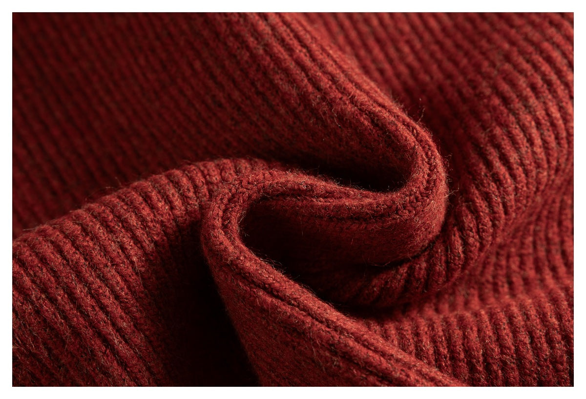 Macro view of folded, thick rust-red rib-knit fabric and its stitched edge.