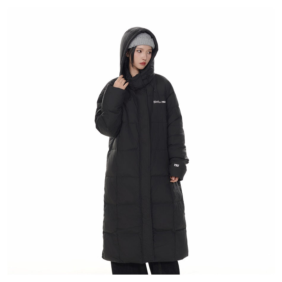 Model wearing a long black hooded puffer coat with white chest and sleeve lettering.