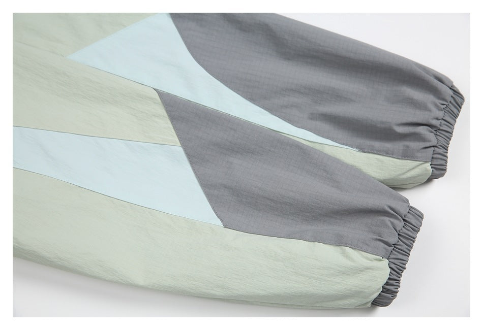 Close-up of color-block pant legs in sage, pale blue, and gray, finished with elasticized cuffs.