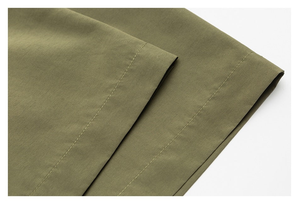 Close-up of an olive garment hem with parallel stitched seams.