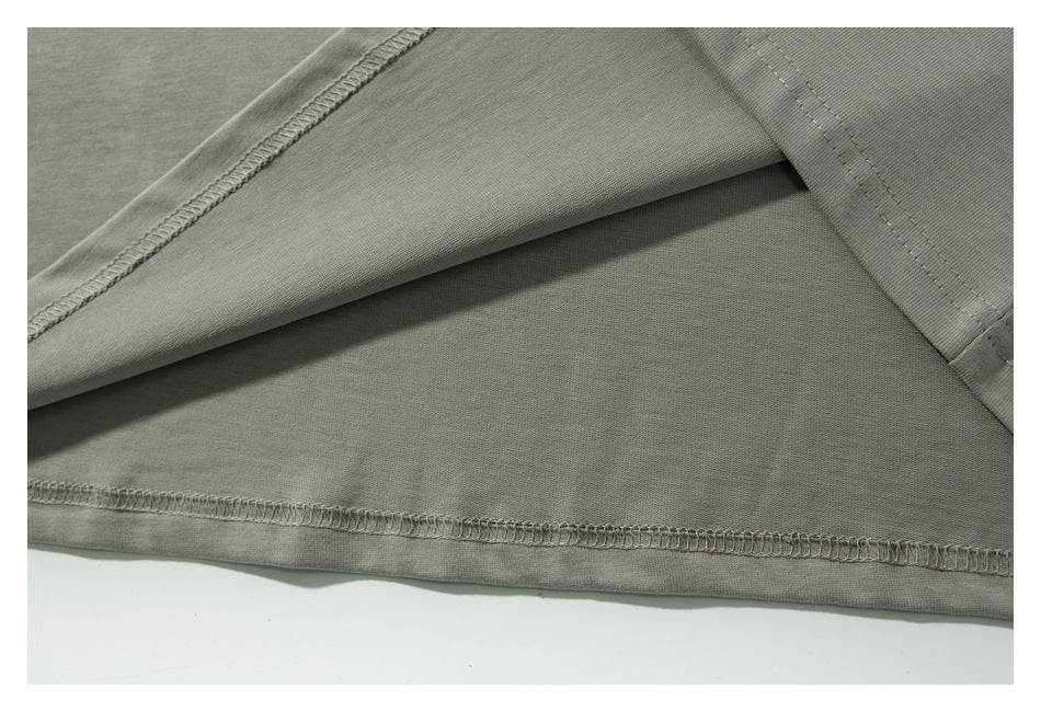 Close-up of a gray garment showing stitched seams and a folded hem.