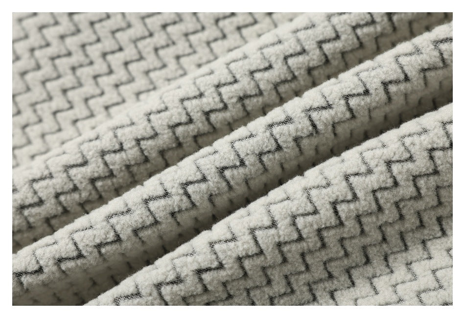 Close-up of plush cream fabric with a repeating gray zigzag pattern, shown in folded layers.