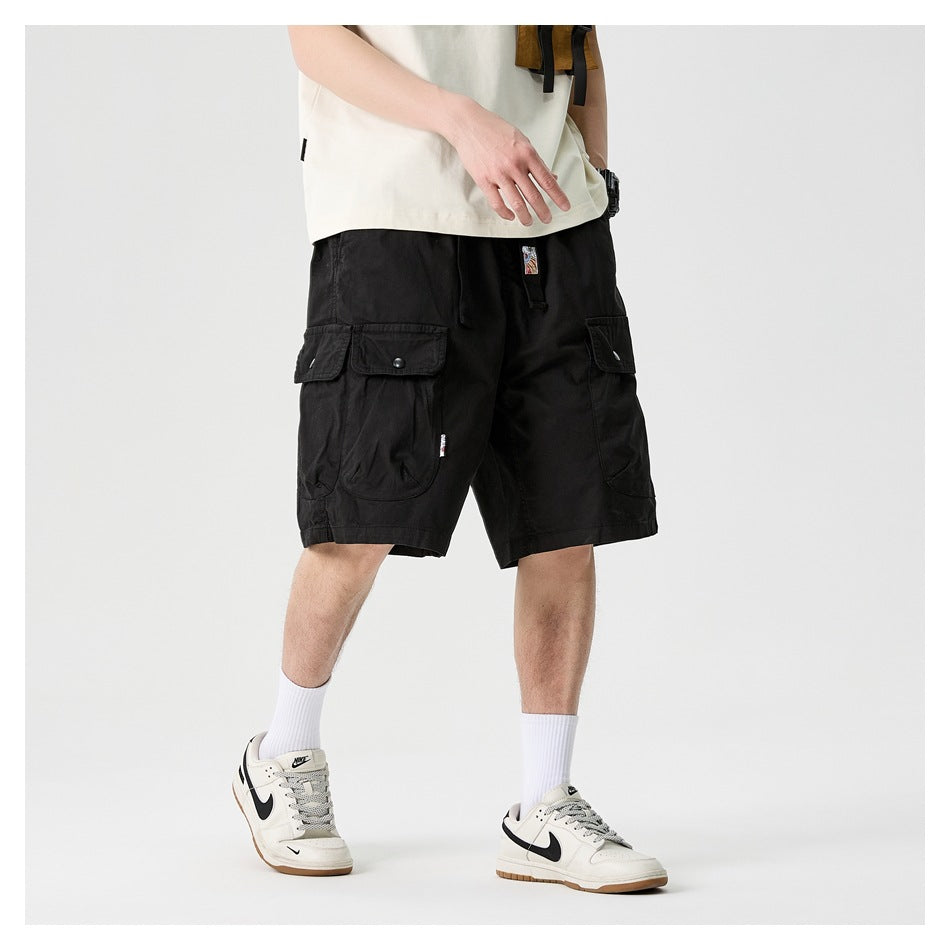 Angled front view of a model wearing black cargo shorts with flap pockets.