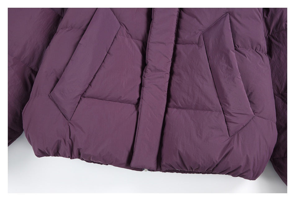 Close-up of the plum jacket's front, showing two large angled pockets and the covered center closure.