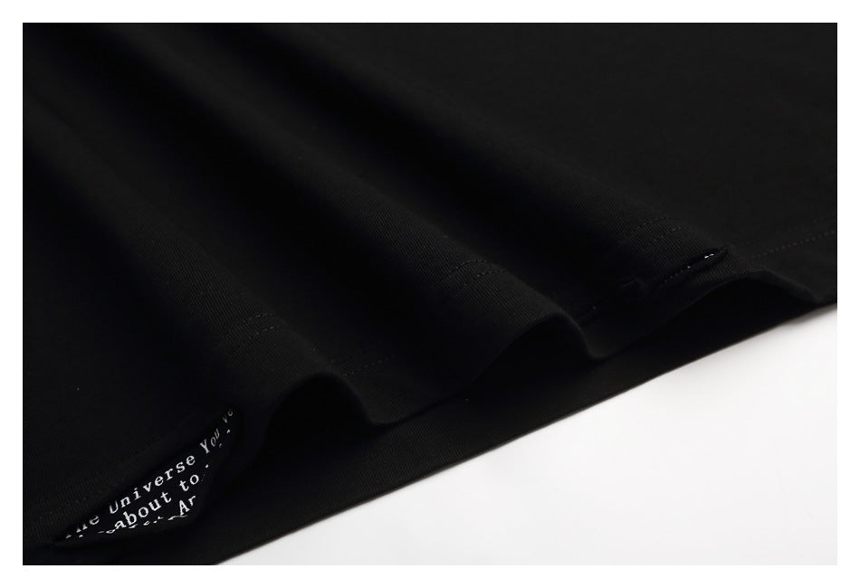 Close-up of folds and stitching on black fabric, with a small text-printed trim visible.