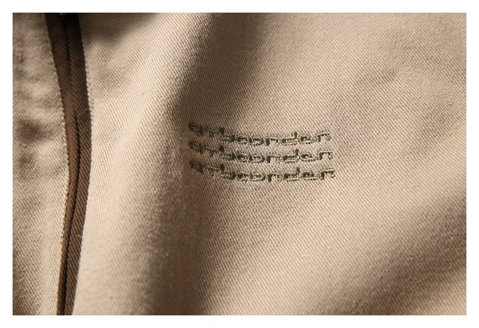 Close-up of small dark embroidered lettering on the tan jacket fabric.