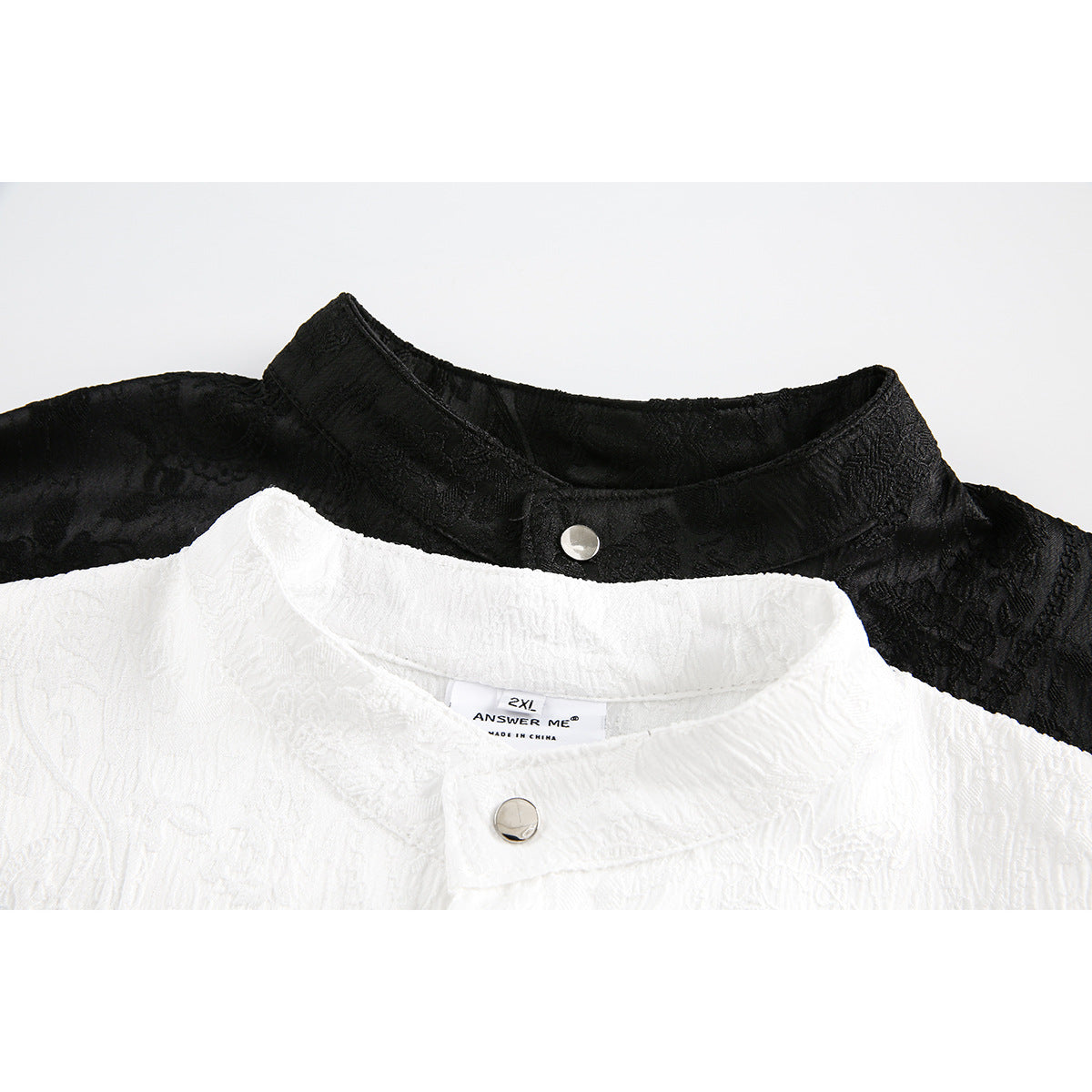 Close-up of white and black mandarin-collar shirts with snap buttons and textured fabric.