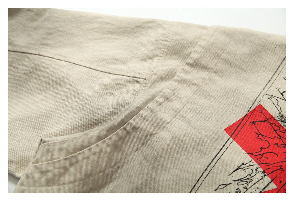 Close-up of a beige jacket seam beside part of a red-and-black printed graphic.