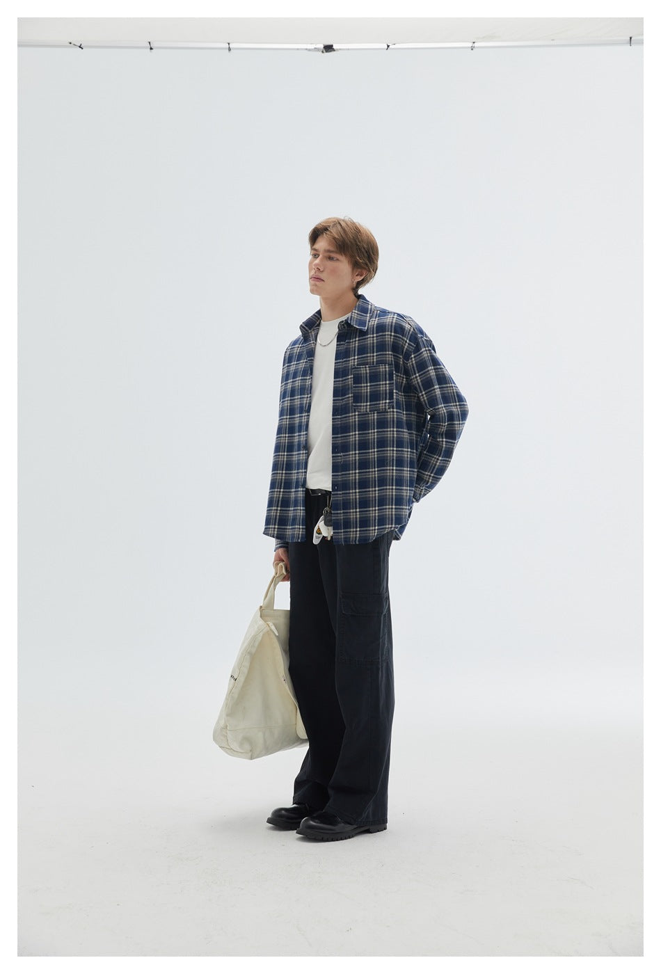 Model wearing a navy plaid button-up shirt over a white tee with black cargo pants.