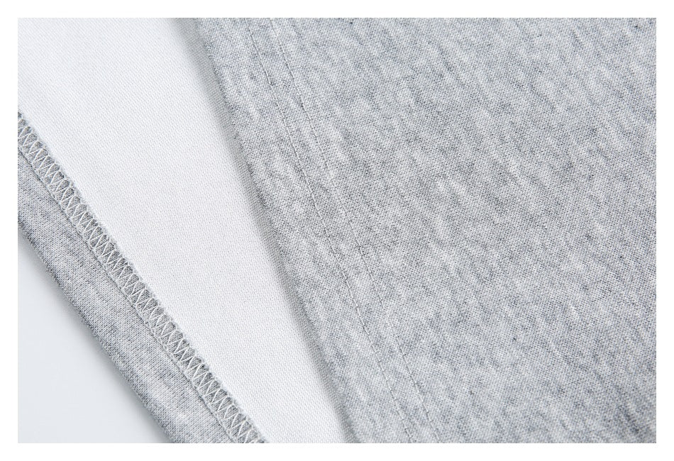 Close-up of light gray heathered fabric with an overlocked seam and parallel stitching.