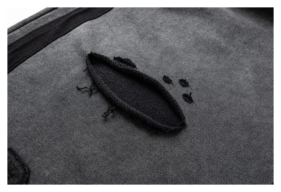 Close-up of a black raised embroidered motif on charcoal gray fabric.