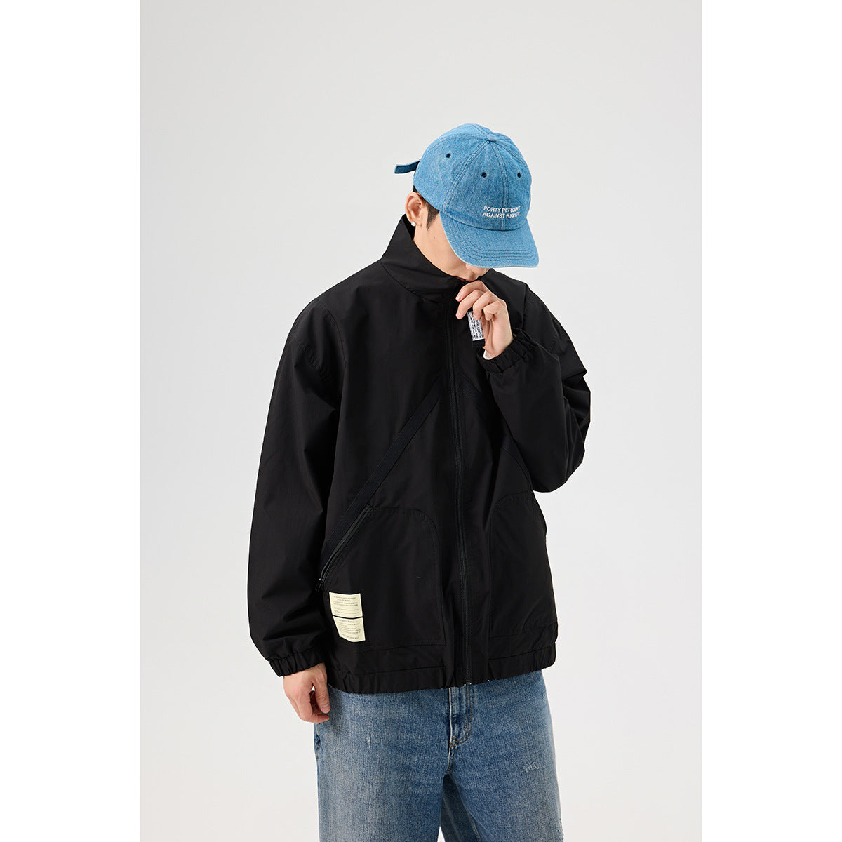 Closer view of a model in a black zip jacket, showing its angled front seams, large pockets, and small labels.
