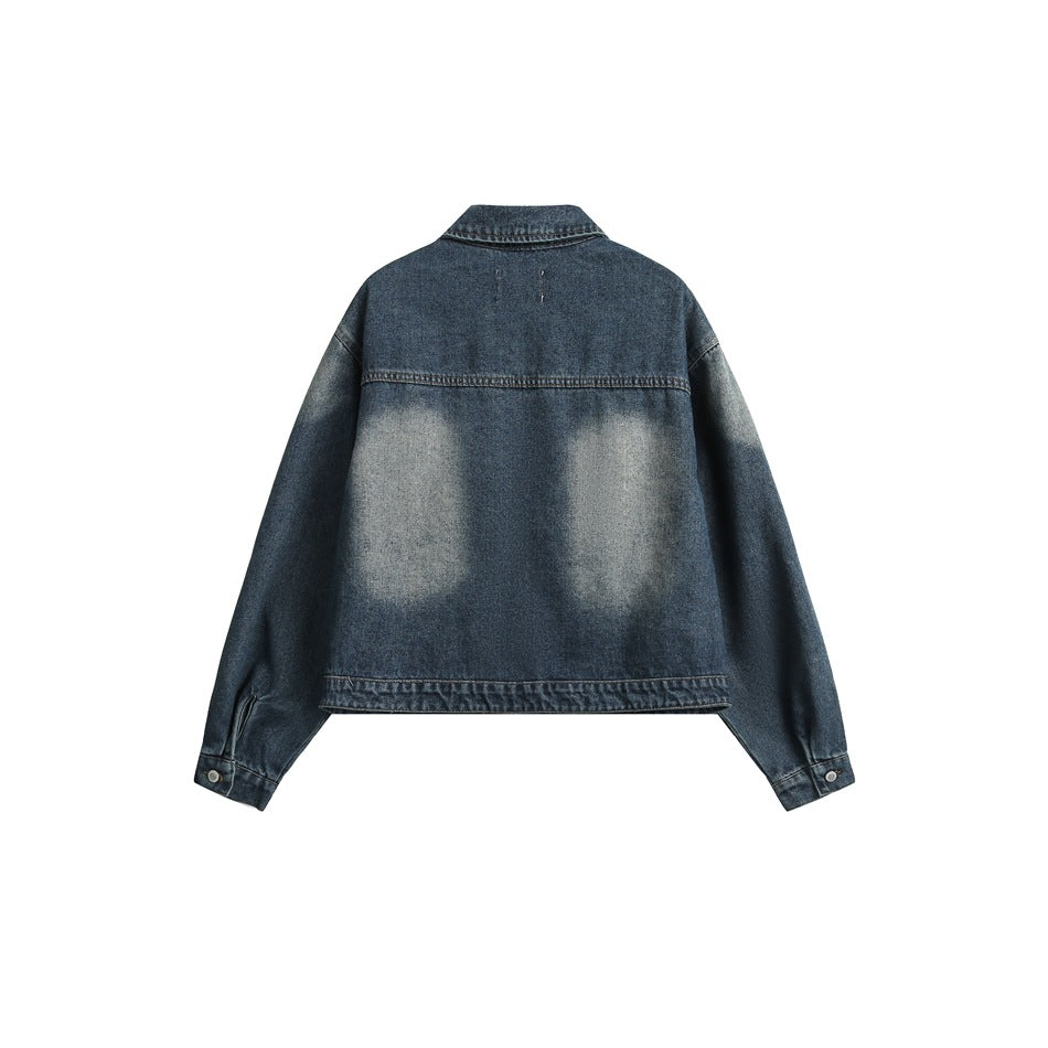 Back view of a blue denim jacket laid flat, with a broad pale washed area across the back.