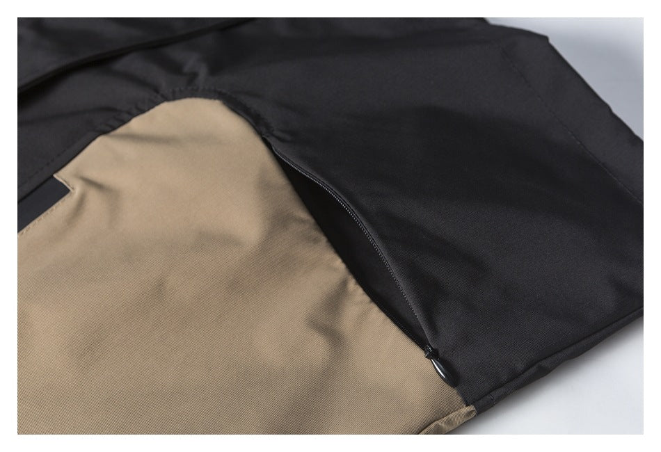 Close-up of a black and tan color-block jacket panel with a curved black zipper.