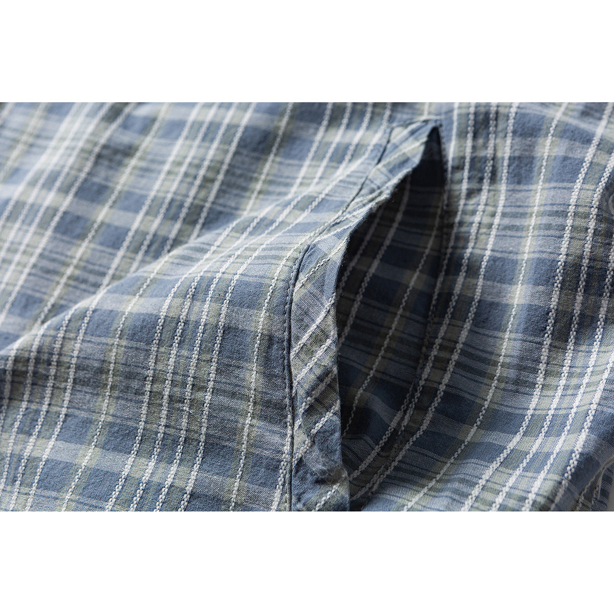 Close-up of a pocket opening on a blue-gray plaid shirt.