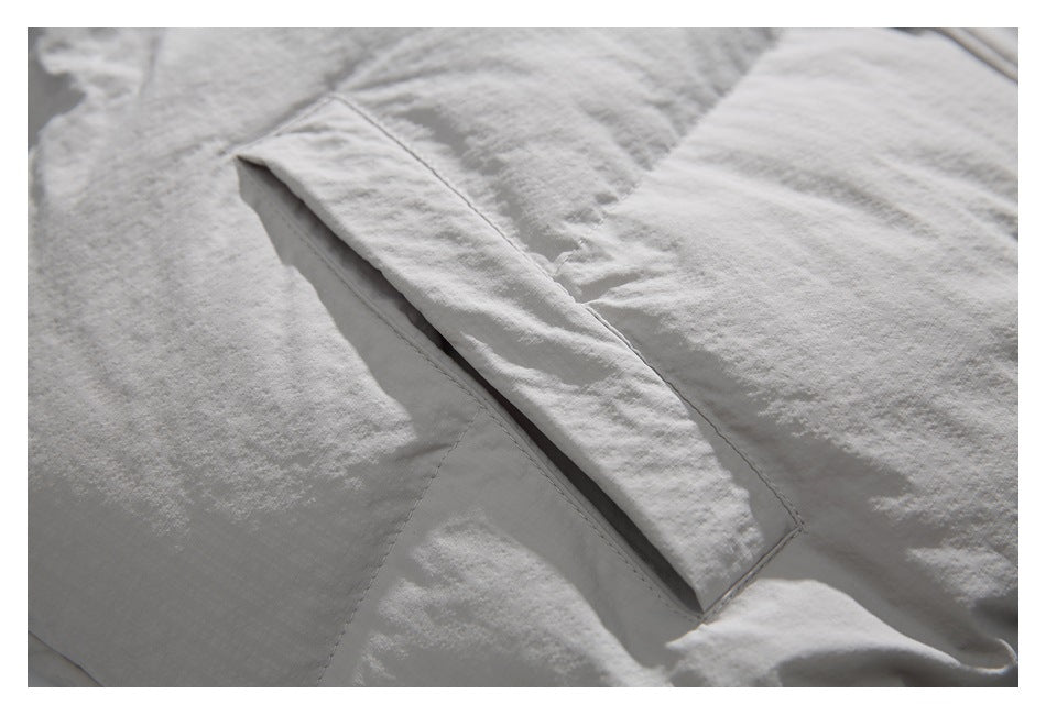 Close-up of a slanted pocket opening on the light jacket.