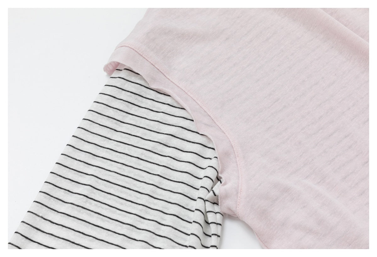 Close-up showing the pale pink top's short sleeve over the thin black-striped underlayer.
