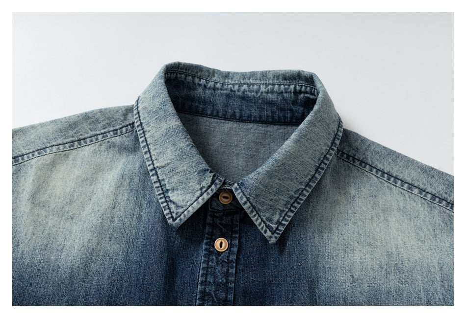 Close-up of a faded blue denim shirt collar, shoulder seams, and tan buttons.