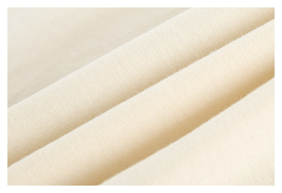 Close-up of cream-colored fabric showing its fine woven texture and folded layers.