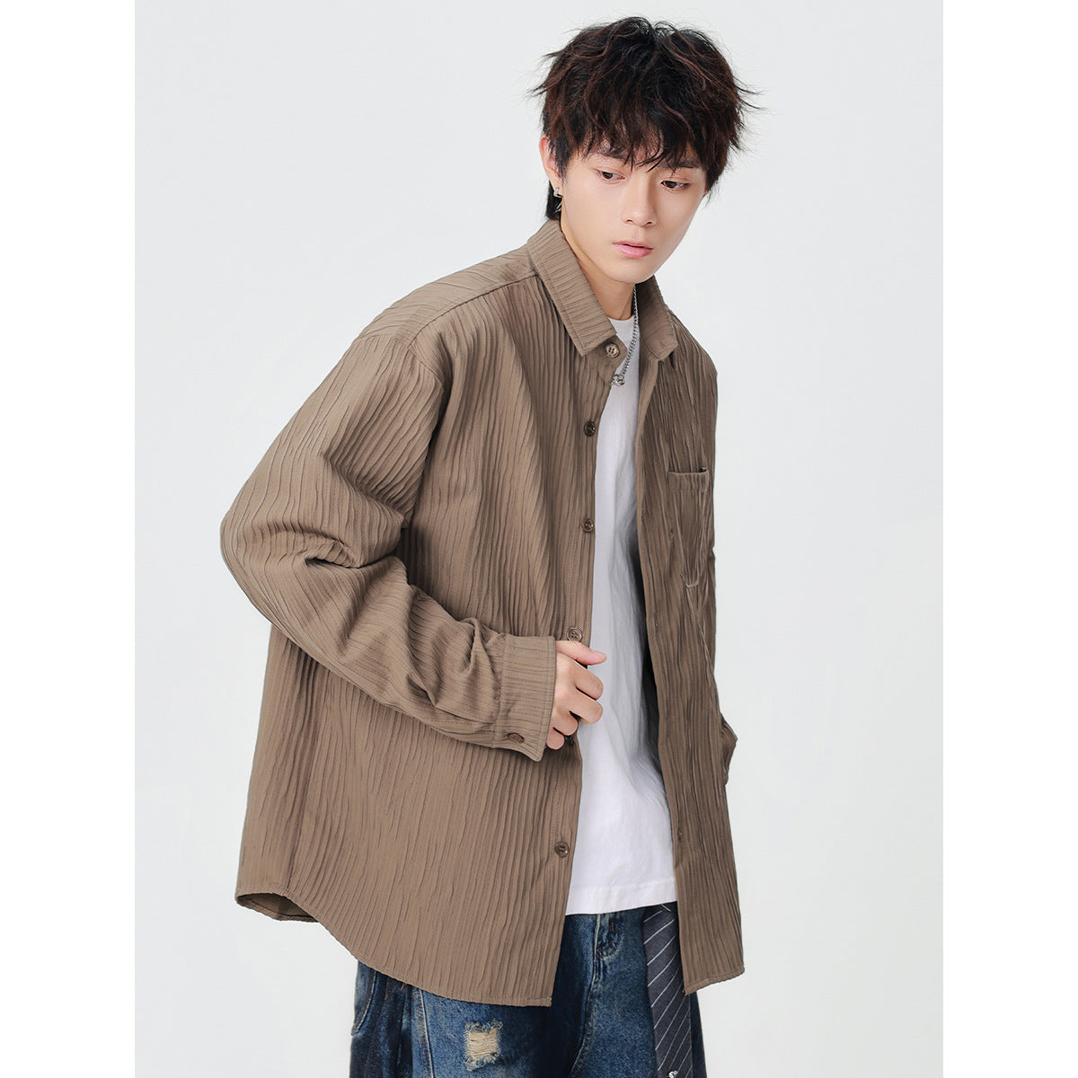 Model wearing a taupe-brown button-up overshirt with vertical texture and a chest pocket over a white T-shirt.