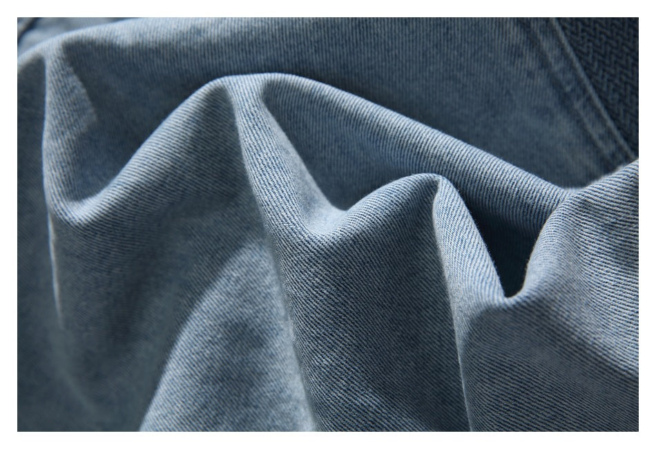 Close-up of blue denim fabric draped into folds, showing its diagonal weave.