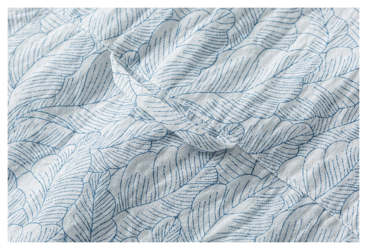 Close-up of pale fabric with blue outlined leaves, gathered into small folds.