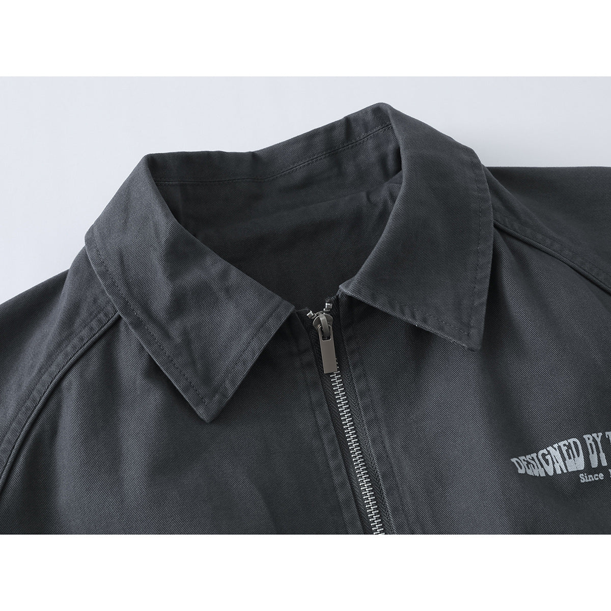 Close-up of a charcoal jacket collar and front zipper, with part of a white chest print visible.