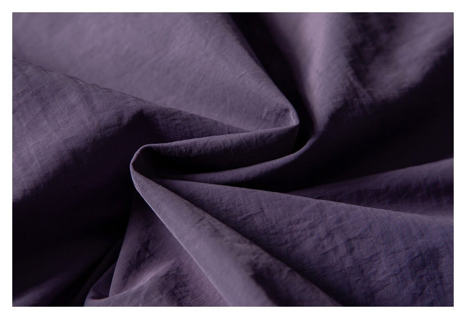 Close-up of purple fabric draped into folds, showing its textured surface.