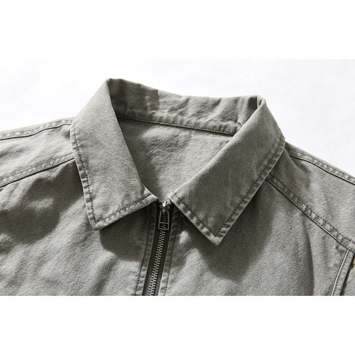 Close-up of a gray washed jacket collar, shoulders, and central zipper on a white background.