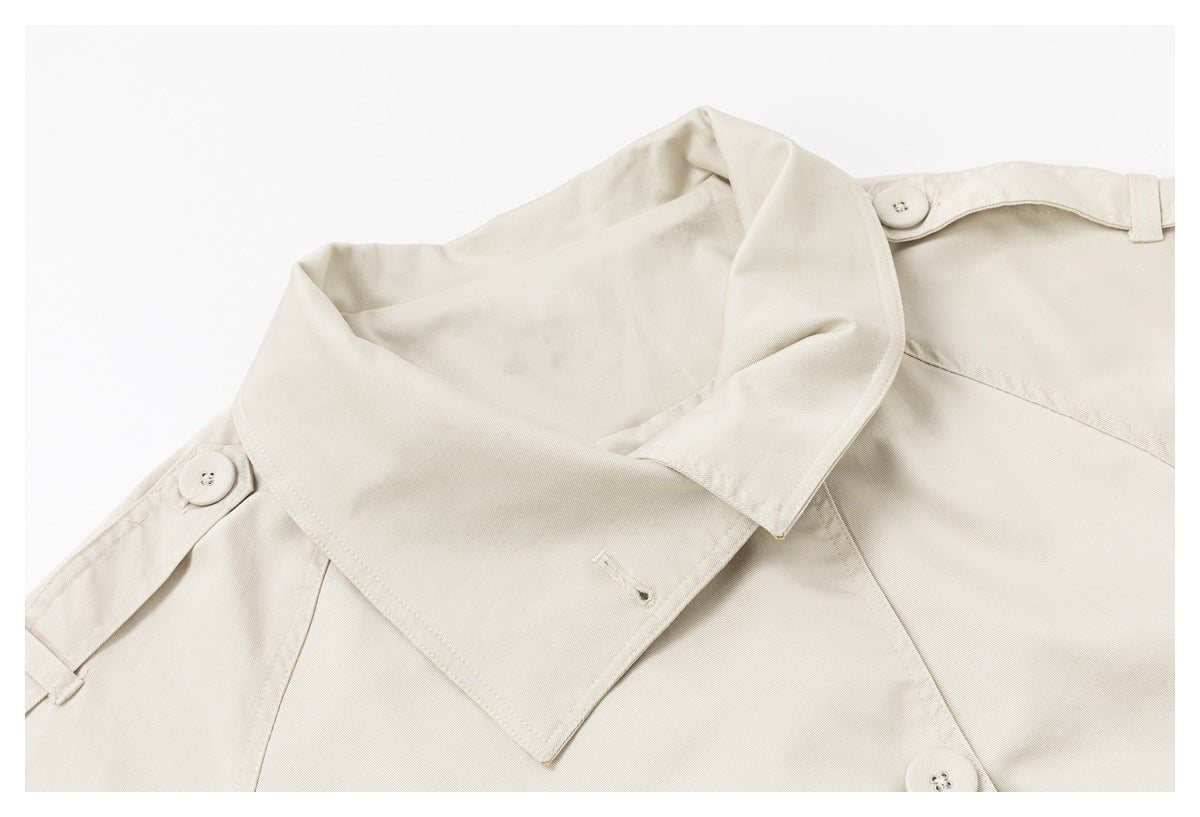 Close-up of a light beige trench coat collar, shoulder tabs, and matching buttons.