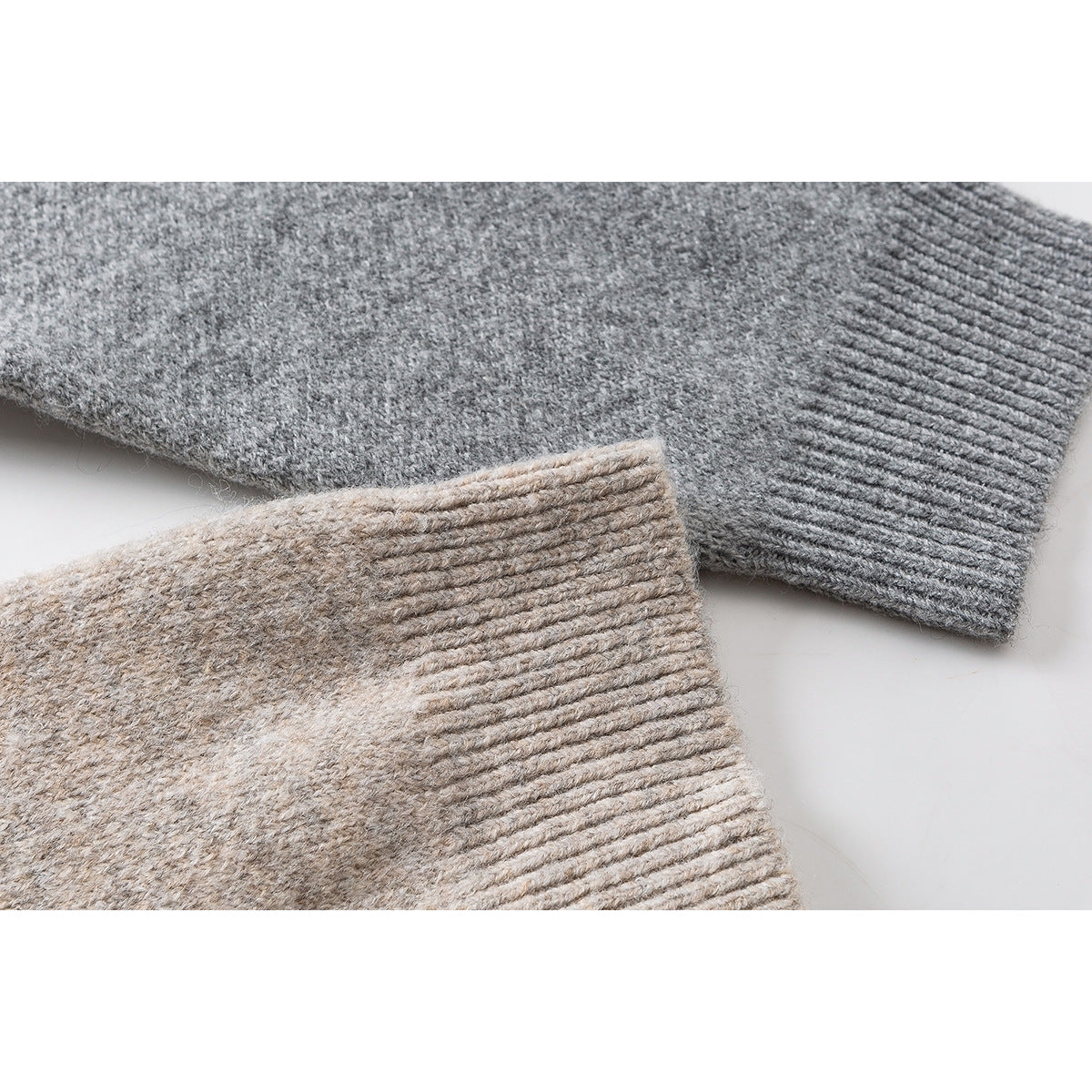 Close-up of gray and beige cardigan sleeves showing textured knit and ribbed cuffs.