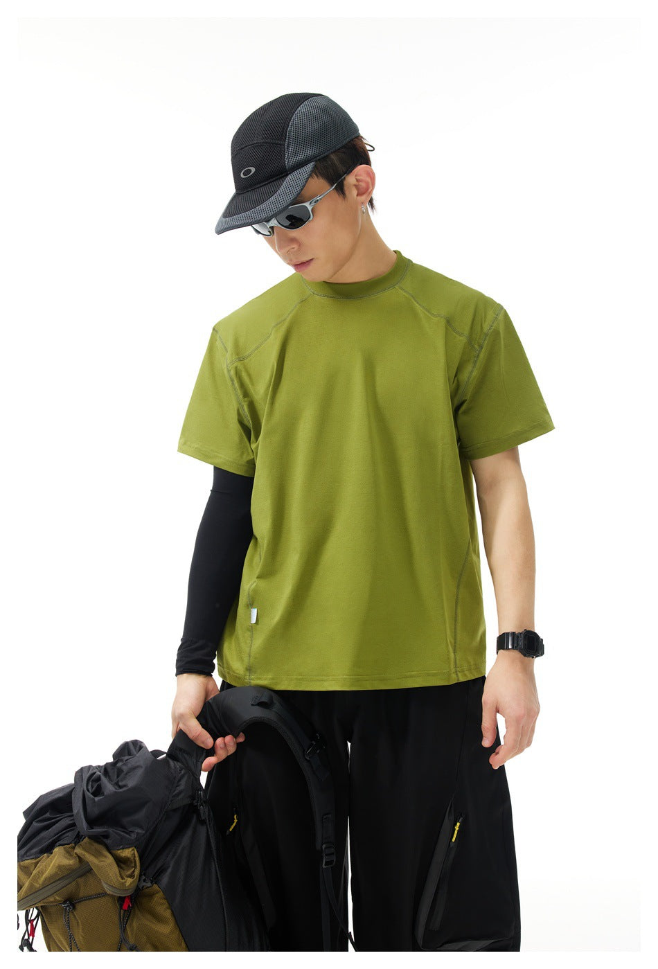 Model wearing an olive-green short-sleeve crew-neck shirt with curved seam details, shown from the front.
