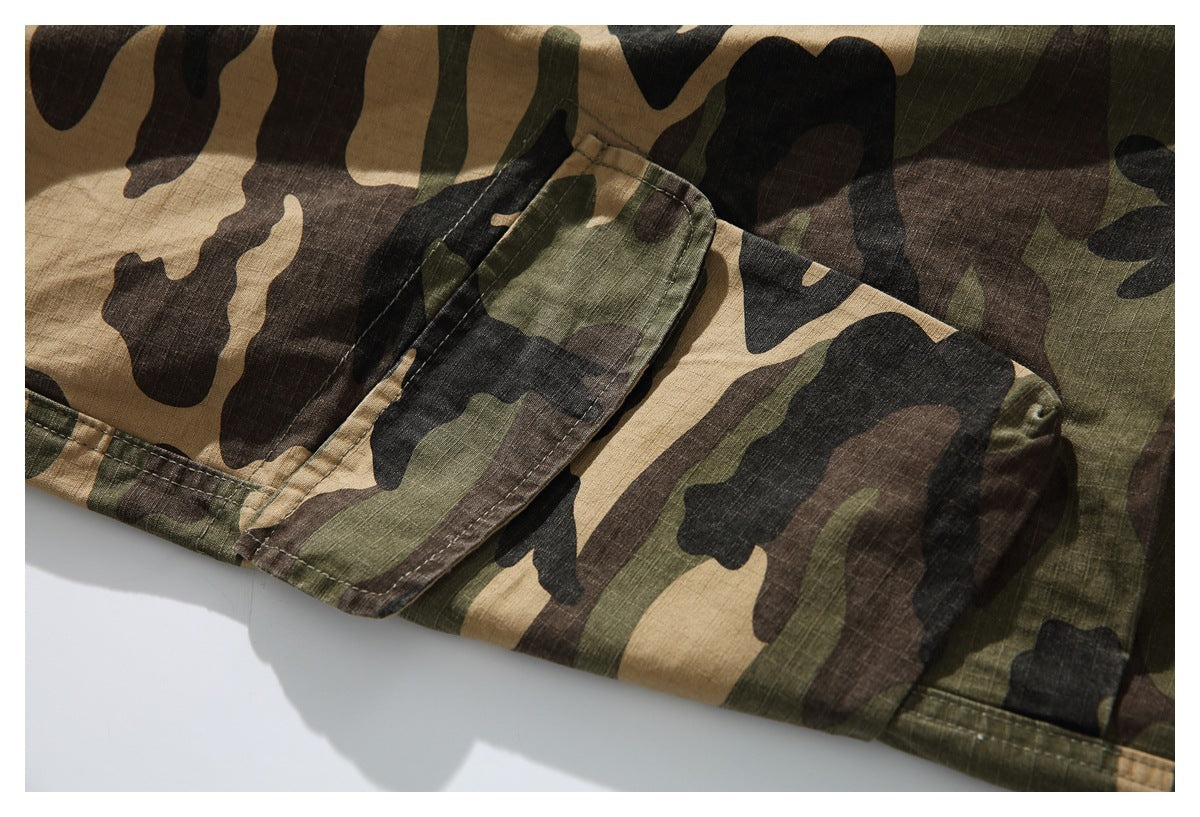 Close-up of camouflage trousers showing a flap pocket and stitched hem.