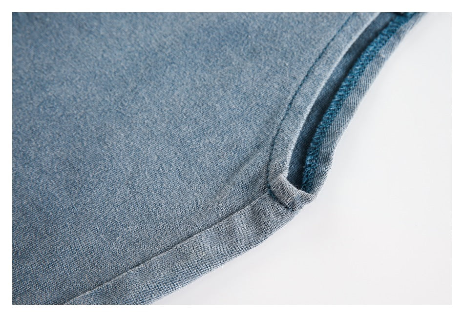 Close-up of blue-gray knit fabric with a bound edge and visible overlock stitching.