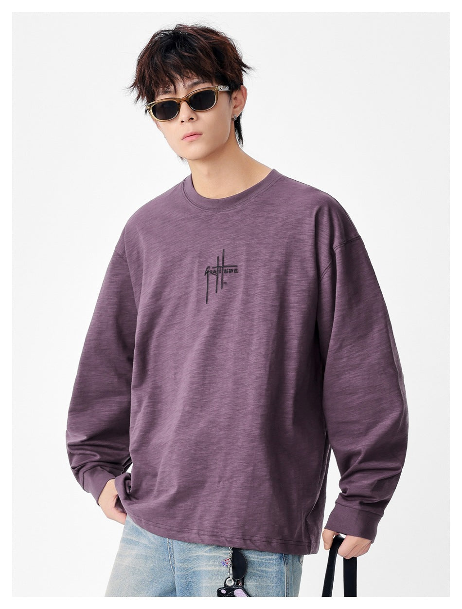Person wearing a purple textured long-sleeve top with ribbed cuffs, sunglasses and light-wash jeans