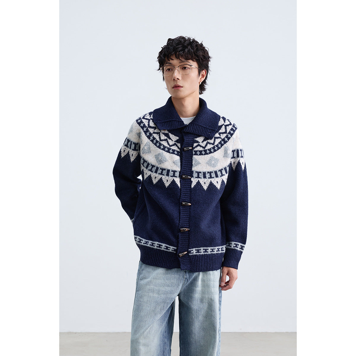 Man wearing a navy cardigan with a wide ribbed collar, toggle buttons and cream geometric bands.
