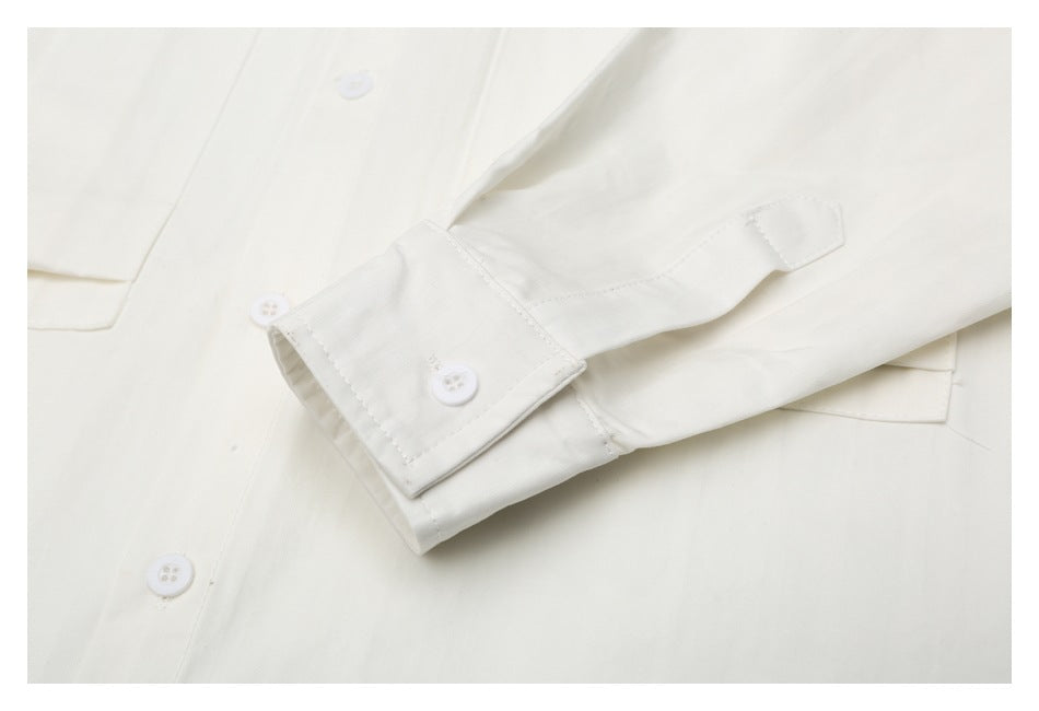 Close-up of an off-white shirt sleeve cuff, button, and nearby pocket edge.