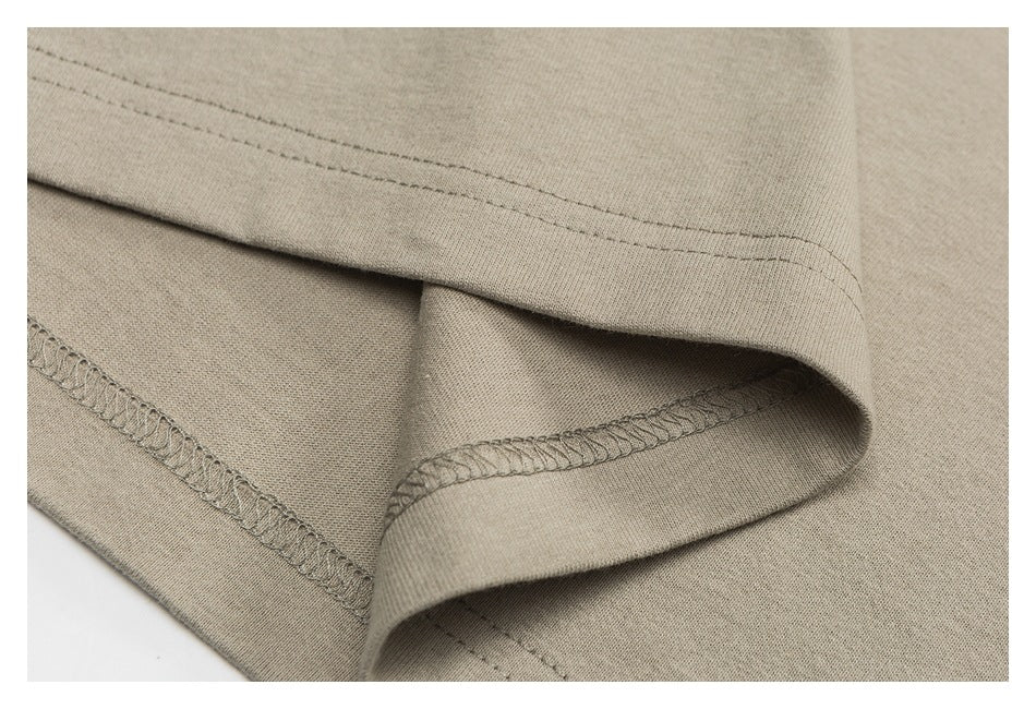 Close-up of a beige garment hem showing double stitching and overlocked seams.