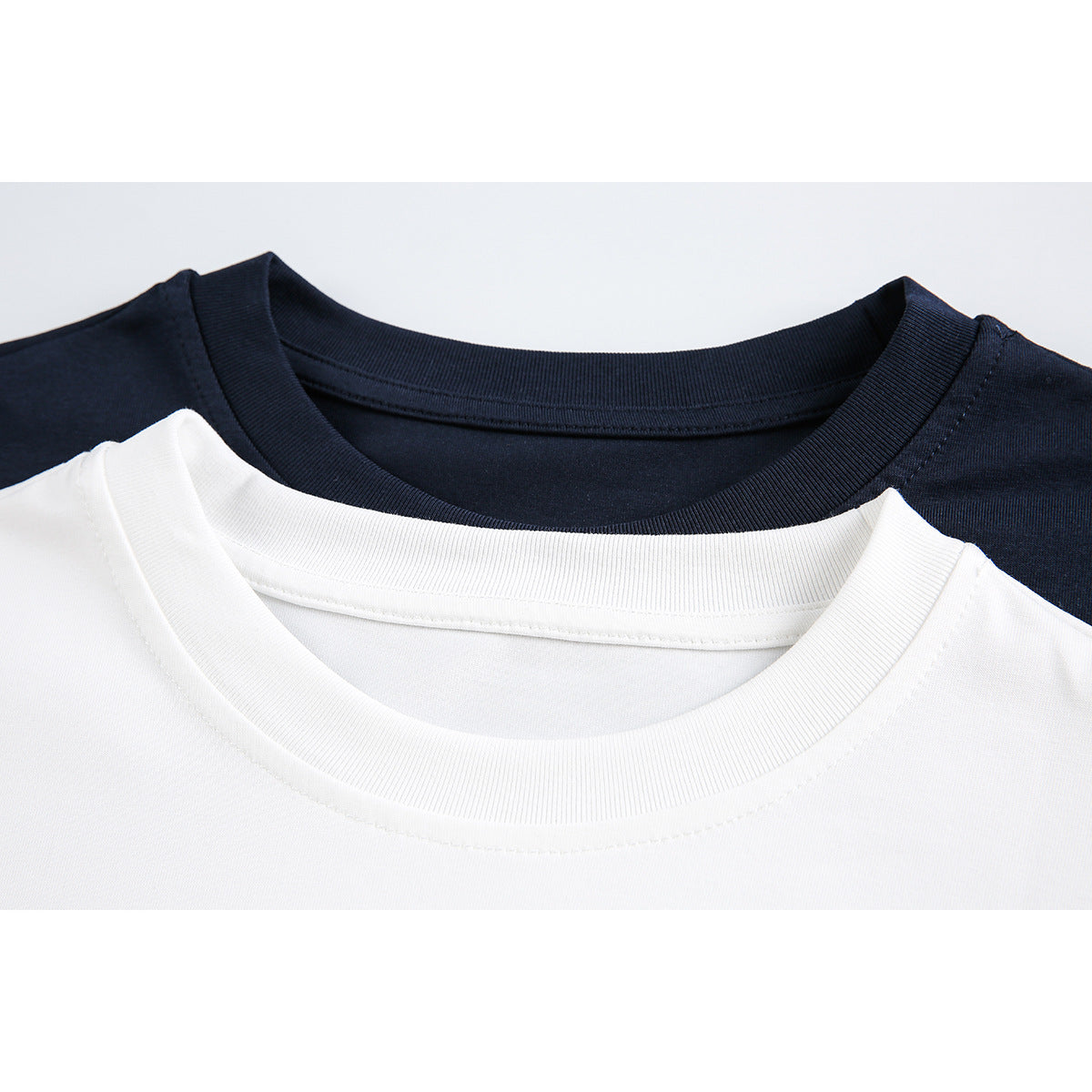 Close-up of white and navy crewneck shirts showing their ribbed collars.